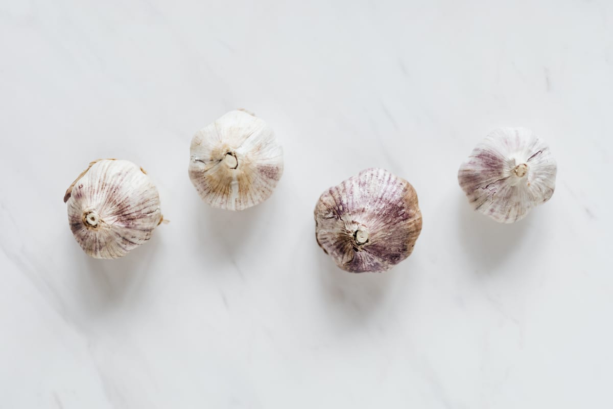 Whole garlic bulbs on a neutral surface, illustrating that garlic is unsafe for dogs
